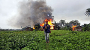 An ethnic Rakhine man holds homemade weapons as he walks in front of houses that were burnt during fighting between Buddhist Rakhine and Muslim Rohingya communities in Sittwe