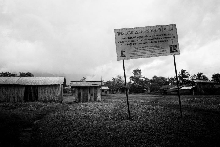 Entrada a la Comunidad shuar de Mayáik, Provincia de Morona Santiago, Ecuador. Cada comunidad ligada a la Federación Interprovincial de Centros Shuar (FICSH), expone un cartel de prohibición de acceso a compañías mineras, madereras, ONG’s y turistas en el territorio shuar y adentro de las comunidades. La FICSH fue establecida en 1965 como una organización apolítica y gestiona y controla el territorio shuar en su defensa y preservación.