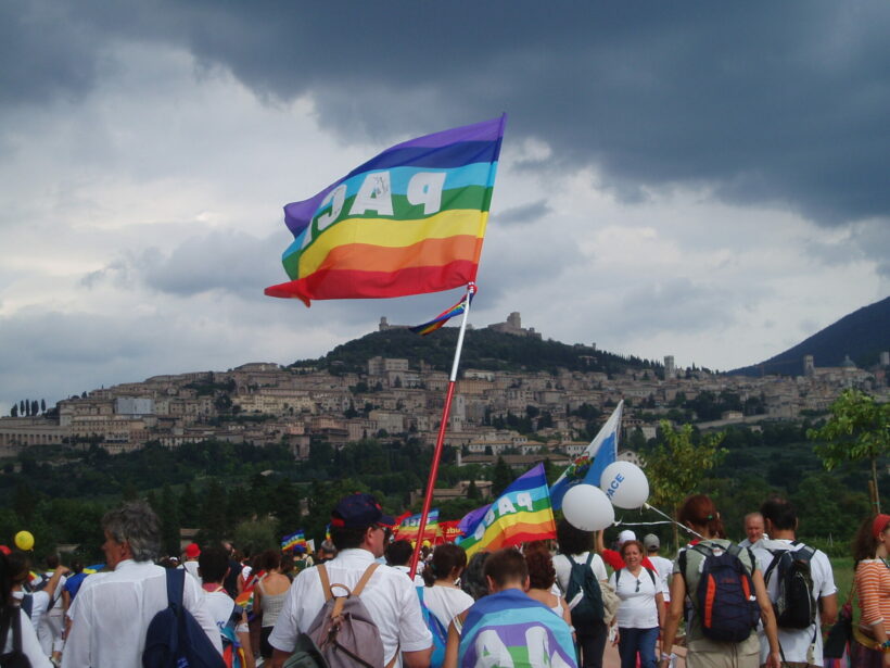 Immagine della bandiera della Pace con una collina e dellepersone in marcia