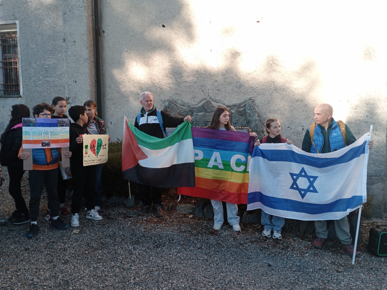 Insegnanti e studenti mostrano la bandiera della pace, quella della Palestina e quella di Israele a Valdilana (BI)