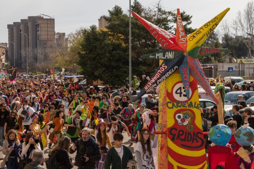 Il corteo del Carnevale sociale di Scampia, promosso dal GRIDAS – Gruppo Risveglio dal Sonno. In primo piano uno dei carri realizzati collettivamente, simbolo di un percorso che da oltre quarant’anni intreccia arte pubblica, partecipazione dal basso e impegno sociale. Il Carnevale del GRIDAS è uno dei momenti più rappresentativi del lavoro culturale portato avanti nel quartiere, capace di unire generazioni diverse e di trasformare le strade in uno spazio condiviso di espressione, memoria e futuro.