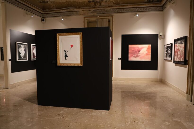 Veduta della mostra “Warhol vs Banksy – Passaggio a Napoli” a Villa Pignatelli. Al centro, “Girl with Balloon” di Banksy, in dialogo con opere di Andy Warhol.