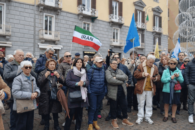 Un momento del presidio in Piazza dei Martiri a Napoli. La folla partecipa in silenzio e con attenzione alla manifestazione di solidarietà con il popolo iraniano. Tra le persone compare la bandiera dell’Iran, simbolo del legame tra Napoli e la lotta “Donna, Vita, Libertà”.