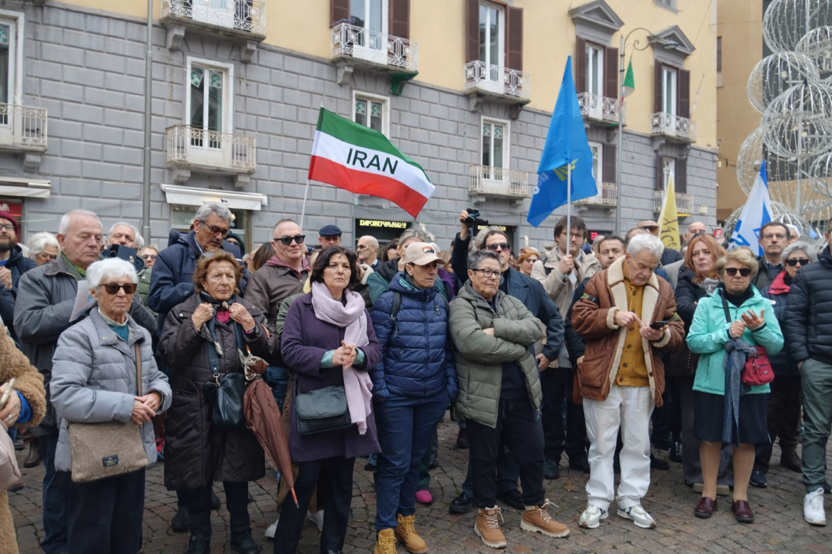Un momento del presidio in Piazza dei Martiri a Napoli. La folla partecipa in silenzio e con attenzione alla manifestazione di solidarietà con il popolo iraniano. Tra le persone compare la bandiera dell’Iran, simbolo del legame tra Napoli e la lotta “Donna, Vita, Libertà”.