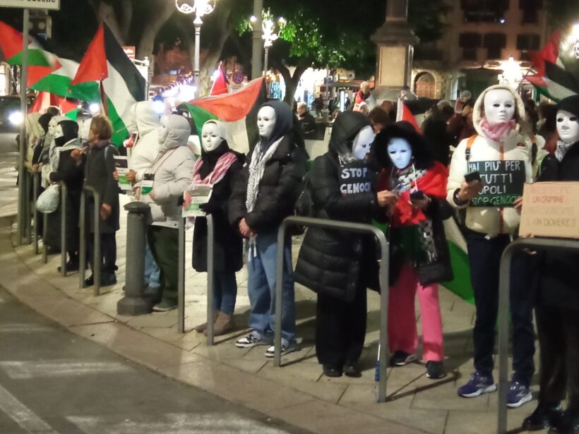 Attivisti pro Palestina, con bandiere e maschere bianche.