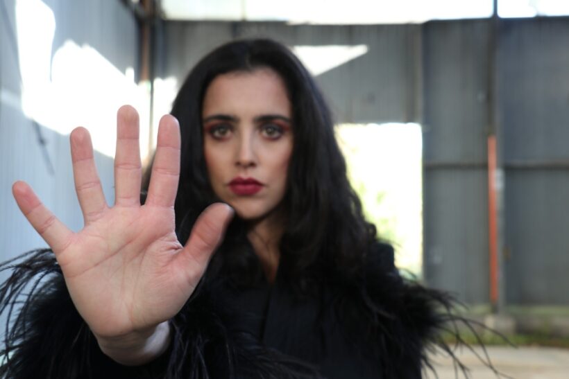 Una mano alzata in primo piano interrompe lo spazio e richiama l’attenzione. Il volto sullo sfondo resta presente ma non dominante, mentre il gesto diventa linguaggio universale di limite, autodeterminazione e consapevolezza. Un’immagine che parla di scelta, rispetto e diritto a fermare ciò che non si desidera.