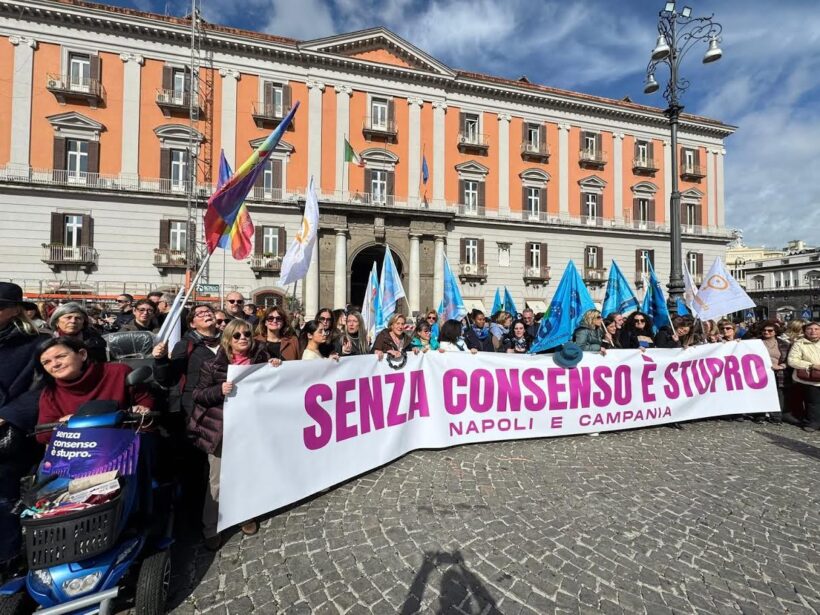Un momento della mobilitazione pubblica tenutasi in Piazza del Plebiscito, a Napoli, con cittadine, cittadini e associazioni riuniti dietro lo striscione “Senza consenso è stupro – Napoli e Campania”. L’iniziativa richiama l’anniversario della Legge 66/1996 e ribadisce il principio del consenso come fondamento nella definizione e nel contrasto della violenza sessuale, in un clima di partecipazione civile e collettiva.