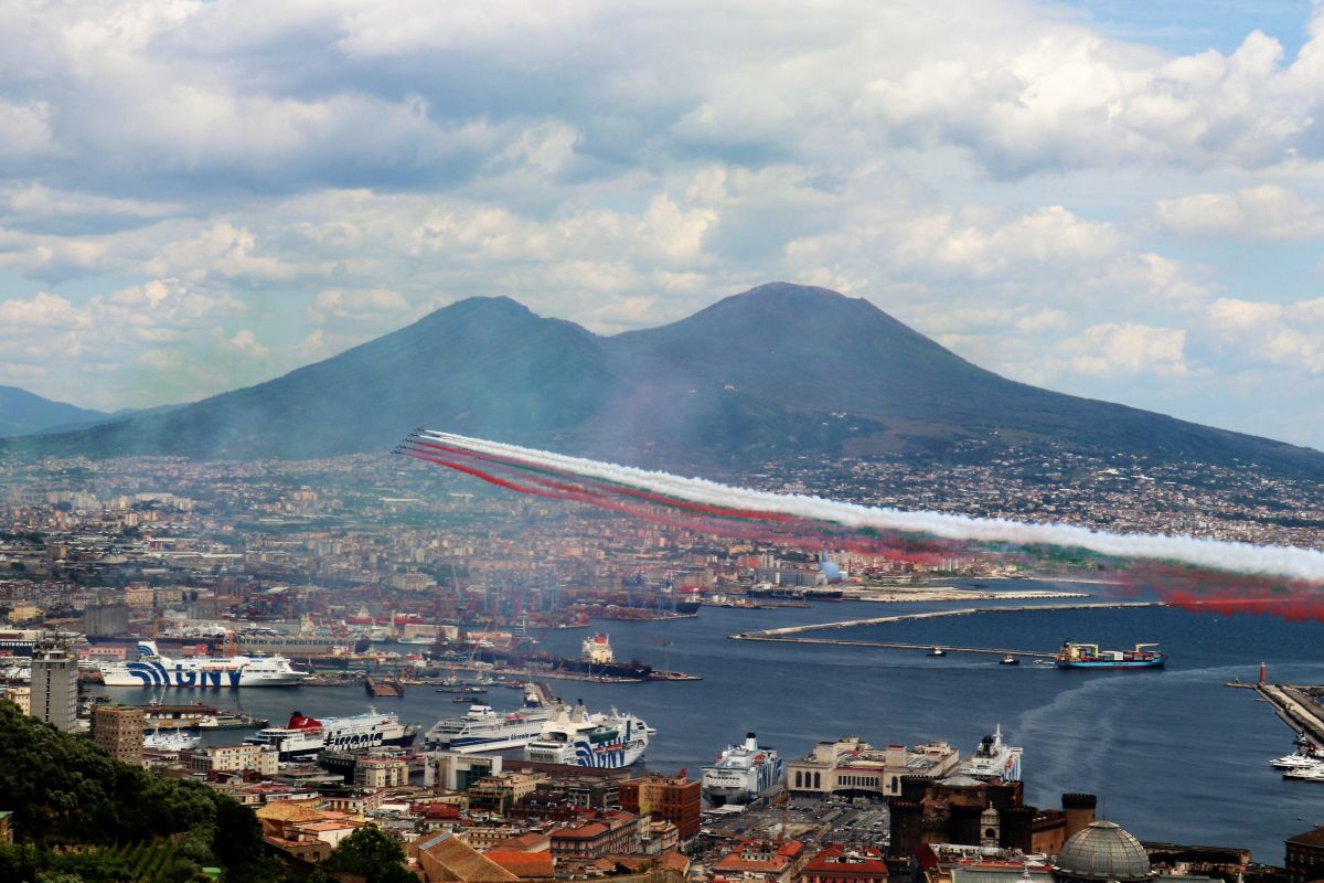 Le Frecce Tricolori sorvolano il golfo di Napoli lasciando in cielo i colori della bandiera italiana, con il Vesuvio sullo sfondo.