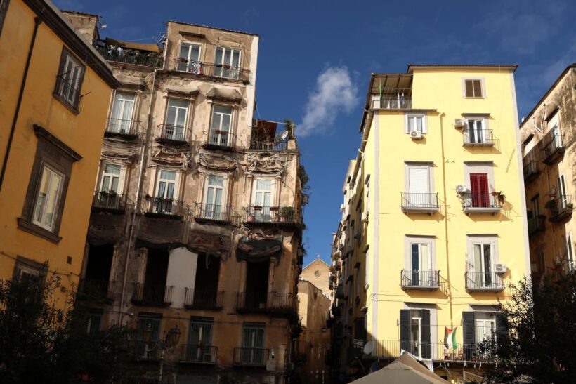 Uno scorcio urbano di Napoli mostra edifici residenziali ravvicinati, segnati da differenti condizioni di conservazione e da evidenti contrasti architettonici. L’immagine accompagna una riflessione sul diritto alla casa, sulle fragilità del tessuto urbano e sulle disuguaglianze che attraversano l’abitare contemporaneo.
