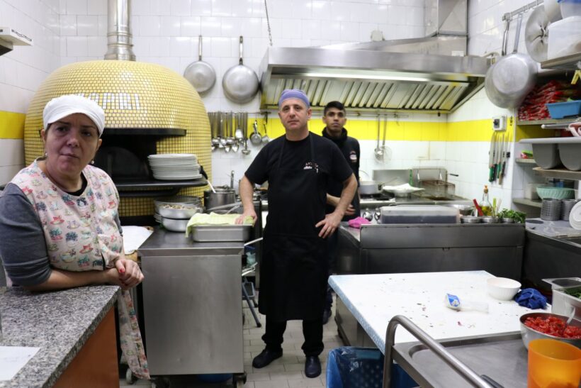 Interno di una cucina professionale con tre lavoratori ritratti durante una pausa o un momento di attività. La fotografia è utilizzata come immagine rappresentativa del contesto lavorativo e non è riferita alla vicenda giudiziaria trattata nell’articolo.