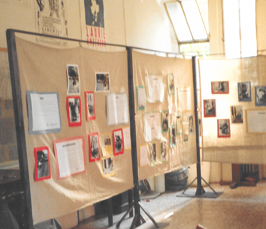 interno con struttura in legno e tela grezza con appese sopra foto e cartelli