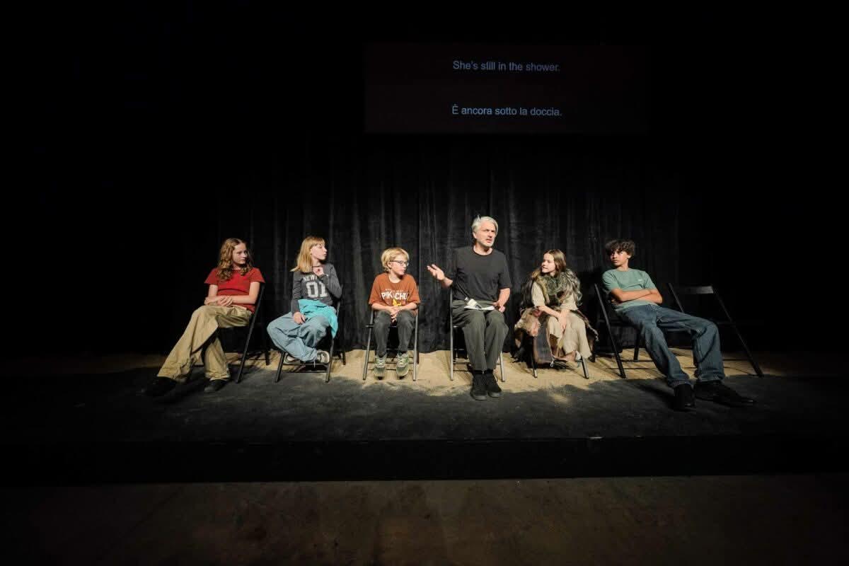 Una scena di Medea’s Children di Milo Rau al Teatro Mercadante di Napoli: in primo piano i giovani interpreti e l’unico adulto in scena, in un dispositivo teatrale che intreccia racconto, straniamento e perturbazione.