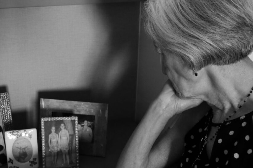 Una donna anziana osserva fotografie di famiglia.