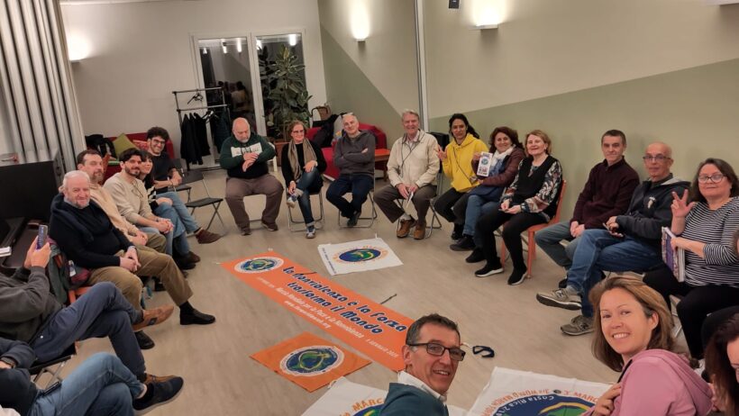 persone i circolo con striscioni e bandiere della Marcia mondiale per la pace e la non violenza