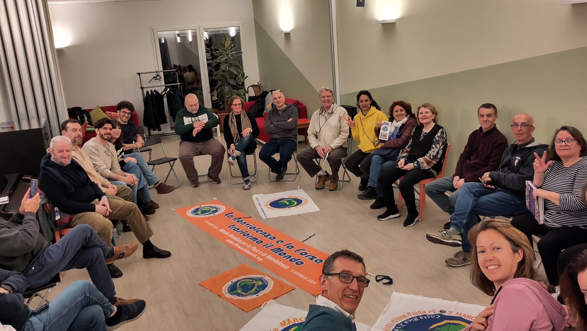 persone i circolo con striscioni e bandiere della Marcia mondiale per la pace e la non violenza