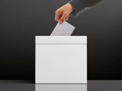 Elections concept. Hand inserting an envelope in a white blank ballot box on black background, copy space. 3d illustration