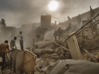 It sounds like a jet approaching, and everybody, it's a matter of instants, stare at each other, your words that choke in your mouth; but it is only a gate that slides and closes. A hatchet chopping firewood is a kalashnikov burst, the footstep of a woman's heel is a sniper shot. We look normal, in Aleppo. Instead, fear is a cancer that wears us out from within.Eight months after the beginning of the battle, one thing only hasn't changed, here: Assad jets are so inaccurate that they never bomb around the front line - they might miss the rebels, and hit the loyalists. And if the favourite target once was the Shifa Hospital, now that its walls are but powder, its medical staff a flower and a framed photo, the most dangerous places are bread lines. They are just kids and women, today. In two hundreds, they compete for a bunch of boxes with some olive oil, some rice, chickpeas. Sugar. They have missing fingers, missing ears, in the sharp wind of this winter's remnants they scarcely wear a threadbare shirt and a few else, their bones that sculpt their skin. Mothers notice you, notice a stranger, and try to leave their newborn in your arms, they say: Bring him with you. Save him.It's starving, Aleppo, swept away by a typhus fever epidemic, in the streets people sell everything, it seems they scattered on the ground their entire living room, teapots, TVs phones, tableclothes, light switches, everything - to be precise: bits of everything: for Aleppo is but rubble, now, someone sells you the stroller, someone else its wheels. Ibtisam Ramdan is 25, she lives with her three children and tubercolosis in a slide of sewer under the river's bank, the door that is a hen-house gate, the fireside a paint's can, and these three children, in the dark of a rancid corner, crying and coughing, they cough so loudly and they cry so desperately that they wheeze - the left-overs of some rice on a cardboard's scrap: they don't even have dishes: and anyway here, for the time being, there's nothing edible. And like them, dozens of other families; all the river's bank is faults and hovels, they aren't sheds, they aren't caves, they are but bits of things, metal sheets, stones, planks, plastic rags - piles, piles of bits of things, at some point, simply, you realize you are inside, amid women, kids, old men, maimed and mute, you walk one centimeter from them and they not even look at you, blackened from the stoves' coal, their feet in the mud. They have but rain water, their skin dotted of infections, even cats, here, are sick, while a jet, suddenly, snarls over your head, you move a shutter, and you find a man who is dying from leukaemia, you move another shutter, and you find a man who is flaying a rat - you ask a question, and your translator who burst into tears and tells you Excuse me, but I have no longer words, I have no longer words for all this.It's so starving, Aleppo, so exhausted that missiles strike, and people continue to live amid the debris. As in Ard al-Hamra, 117 dead - 17 of whom are still here, scattered under you. The alive pop from collapsed stairs, collapsed ceilings, one by one, from crumbled pavements, butts of pillars, a carpet that hangs from a chandelier: they have only what they wear, in the Nokia of Fouad Zytoon, 36, the picture of a head hurled on a shelf, it's his daughter. They insist on telling you everything in detail, Do you want the names of the victims?, they ask you, I got the complete list, and you feel ashamed to say it, but no, you don't need the names, the number is enough, and anyway it's late, and Aleppo is thousand stories and this is just a line of your article, it's late, really, and anyway you are tired, and dusty, and you are scared of this jet over your head, that keeps on circling, and circling and circling, the pilot who is selecting his target, who is perhaps selecting you and no, you need only the number, thank you it's enough, 117, 17 never recovered from under your feet - and the guy, point-blank, who stares at you, tells you: You see? nothing remains, of our lives, not even a name.It looks normal, Aleppo. And journalists left. War has become so part and parcel of this city, so embedded in its flesh that grass grew amid the rubble, taxi drivers notice the Nikon, on your neck, and they stop you, as you were a tourist, they ask you: Want to go to the frontline? - but then you bump into a kid, and she salutes you standing at attention: you bump into a garbage collector, in the street, into an electrician who is fixing an antenna, and it's like a whip crack, suddenly, the body that falls down: shot down: a sniper. Then at the entrance of the hospital, while the jet disappears, appears, glides, gains altitude again, at the entrance of the hospital lie the corpses with no ID, people pass by, they just lift the white sheet, they make sure he isn't a brother, a cousin. Then you walk into a playground, while perhaps he is selecting you, and there is a sleeping bag amid the swings, while perhaps it's your turn, and in the sleeping bag there is a black-and-blue guy, a hole on his temple, then you open a main door, and the walls that are all blood, while they are the fiercest minutes, you look around, and everywhere, these buildings that are one floor inhabitated one floor destroyed, a charred tricycle pending in the air. Then you go into a school, into a classroom, and at mortar fire's noise, children not even turn their heads: only at a rain of kalashnikov fire they start to debate: It's a doshka, Ahmed, 6, says, No it's a short-barrell kalashnikov, Omar, 6, too, says, You see?, it's lighter than a draganov - while perhaps it's your turn, now, and you can only hug yourself, together with all you didn't say, in your life, the times you weren't able to love, the times you weren't able to dare, the times that now it's late for everything, and life shines of a raging beauty, now that perhaps your turn has come. Until you get the news; airstrike on Sheik Said neighborhood. And it's rough to admit it, but it's an infinite relief: Sheik Said: not you - an infinite relief: to know that somebody died. And - and it's like this war has robbed you not of your humanity, but even more violently: like it left you naked in front of the mirror: naked as you really are: because you are the only one who matters, in your life, to admit it bleeds, but this war hasn't robbed you of anything, simply your humanity, your diversity never existed. You are the only one who matters - and such a life, what a life is?Because later, worn out, you twist and turn amid the piled sandbags to escape the never ending snipers. How long does it take?, you ask, your nerves crumbling, how far is it? - and only now you do understand this war; when in the middle of nowhere, Alaa says: It's here.Because of the ancient souk of Aleppo, the most charming 4,000 sqm of the Middle East, a vertigo of voices, and tales colors, an overflow of life, now this is all that remains: rubble. Your feet that you walk in and sink until the ankles, bented spikes of rusty iron bars, shattered glasses, metal sheets, bullet-ridden blown up shutters. Powder and stones. Nothing else. But really nothing else. Rebels drag you around alley by alley; this is the cotton market, they explain you, this is the gold market, on your right you find the spices, down there is the silver. And they are but rubble. Here is where brides buy their gowns, and they point out the butt of something, here their wedding band - verbs in present tense: and you see but nothing. There's not even a rat, here.Rebels and loyalists are so close that they scream at each other while they shoot each other - it's a war of the last century, the war of Aleppo, it is a trench warfare of rifle shots, on the frontline the first time you cannot believe it: with these bayonets that you have seen only in history books, and you tought they hadn't been used any longer since Napoleon's time, today that war is a drones war: and here, instead, they fight meter by meter, with that blade tied to the barrel, and decayed of blood, and for it's really a war street by street, a hand-to-hand combat, the alley cats, out there, that contend for a shinbone. Even tough they are but praetorian guards of an empire of death, by now, ready to offer you tea and cigarette under the sun and fire while from the old mosque, a UNESCO world heritage site, they welcome you with the V victory sign as in front of the Colosseum for a photo souvenir: and instead they are but in front of smashed minarets, walls defaced by bullet holes, briers of rubble while they take off their shoes, as in any mosque, or they stop you: You cannot enter here: this is the women area, and instead they are but the charred remains of objects you don't even understand what objects are - while they keep guard pink elephants: but everything, here, amid the ghosts of the brides, is more sacred than life.You think they are roads, they are The Road by Cormac McCarthy. Even the muezzin, now, calls no longer to prayer: he calls for blood donors for the wounded of the last missile, dropped one hour ago. And only kalashnikov fire, suddenly, wake you up - out there shooting starts again. It is the only sign of life - out there, somebody dies. Somebody hasn't died, yet.