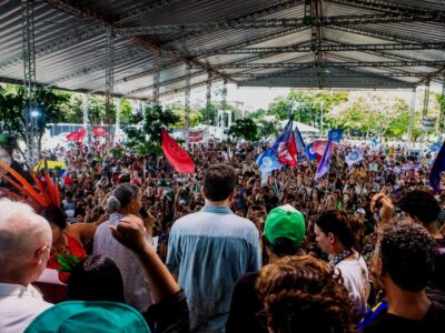 Rear view of several speakers facing a crowd of hundreds at a protest rally at COP 30 People’s Summit.