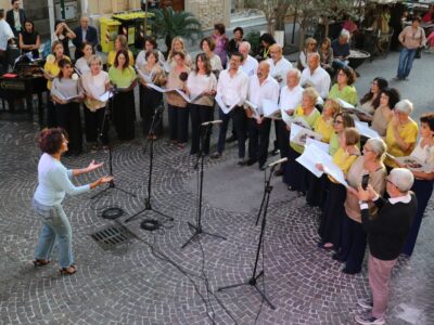 Il coro IoCiSto APS, diretto da Francesca Curti Giardina, durante una performance pubblica a Napoli, in un momento di musica condivisa e partecipata.