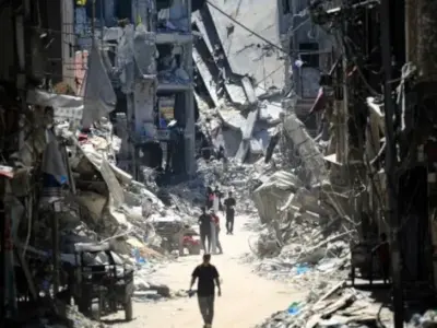 Palästinensische Männer gehen am 11. Juni 2024 eine enge Straße entlang an zerstörten Gebäuden in Khan Yunis im südlichen Gazastreifen vorbei (www.brasildefato.com.br)