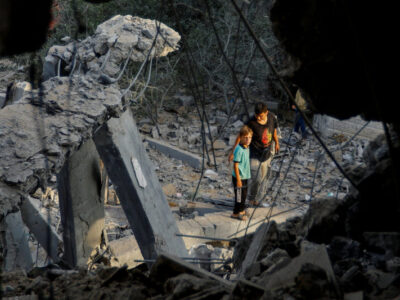 Palestinians stand on the rubble near a damaged house, following Israeli strikes, in Khan Younis in the southern Gaza Strip October 11, 2023. REUTERS/Ibraheem Abu Mustafa