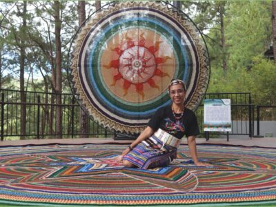 Pine-kissed solar mandala looms vertically in the background, enhancing Adelaida Guia's largest crochet masterpiece at Dagitab Amphitheater’s floor. The artist beams with pride!