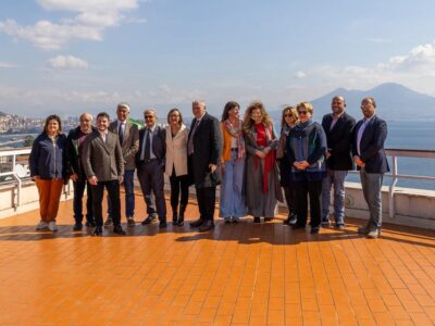 Foto di gruppo dei rappresentanti delle istituzioni, della cooperativa L’Orsa Maggiore e dei partner del progetto durante la presentazione di Casa GLO, nella villa confiscata al boss Michele Zaza. L’iniziativa segna un nuovo sviluppo del riutilizzo sociale del bene, con percorsi di inclusione, agricoltura sociale e comunità energetica, in un contesto panoramico affacciato sul Golfo di Napoli.