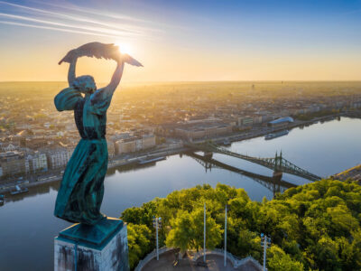 Aerial view from the top of Gellert Hill with Statue of Liberty, Liberty Bridge and skyline of Budapest at sunrise with clear blue sky