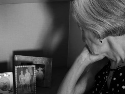 Una donna anziana osserva fotografie di famiglia.