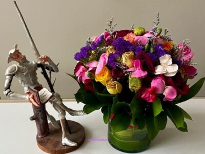 Un don Quijote dedicado a la lectura junto a un ramos de rosas de colores